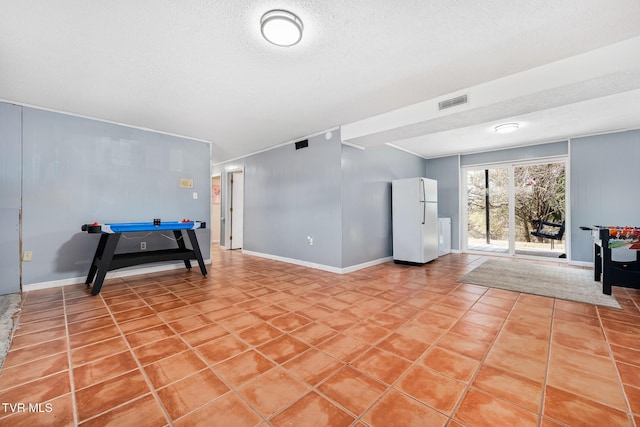 recreation room with light tile patterned flooring, baseboards, visible vents, and a textured ceiling