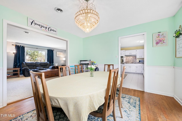 dining room with visible vents, an inviting chandelier, and light wood finished floors