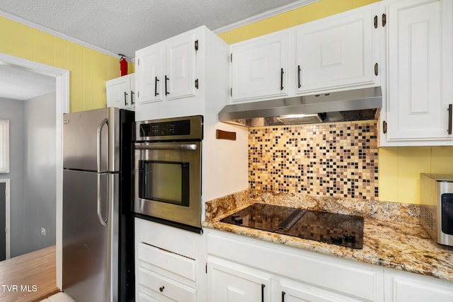 kitchen with under cabinet range hood, backsplash, appliances with stainless steel finishes, and white cabinetry