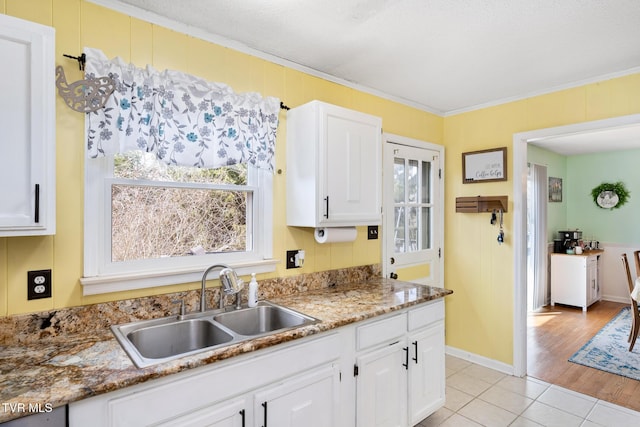 kitchen featuring crown molding, white cabinets, a healthy amount of sunlight, and a sink