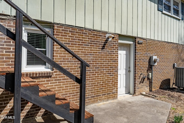 doorway to property with central AC unit and brick siding