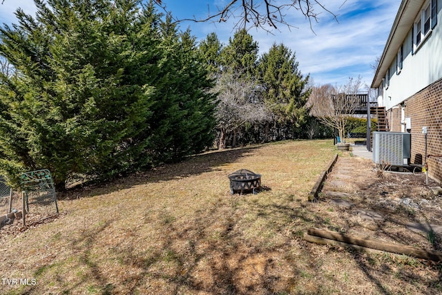 view of yard with a wooden deck, stairway, central AC unit, and an outdoor fire pit