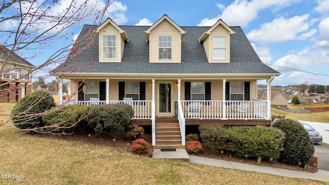 new england style home featuring a porch, a front yard, and a shingled roof