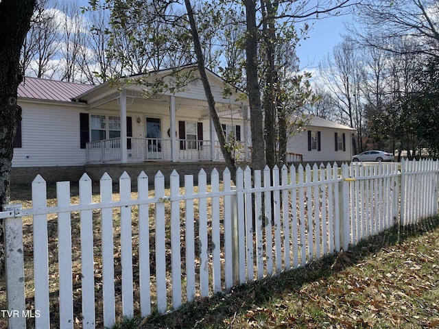 view of front of home with covered porch, a fenced front yard, and metal roof