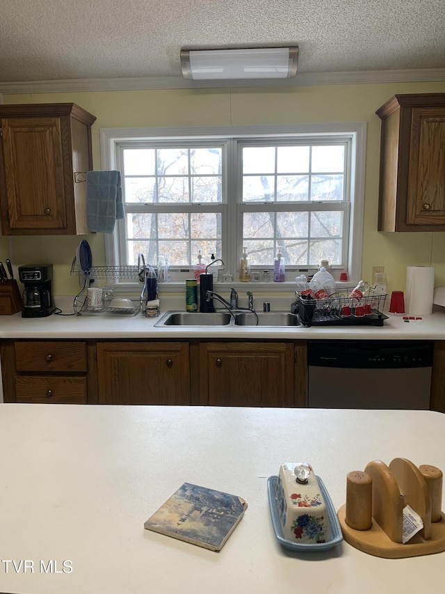 kitchen with dishwasher, light countertops, ornamental molding, and a sink