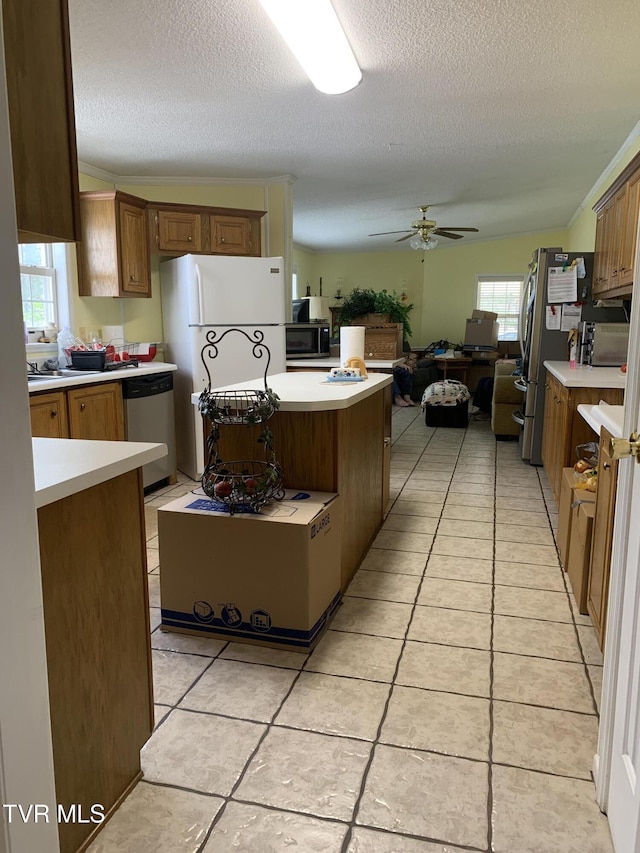 kitchen featuring open floor plan, light countertops, light tile patterned floors, stainless steel appliances, and a ceiling fan