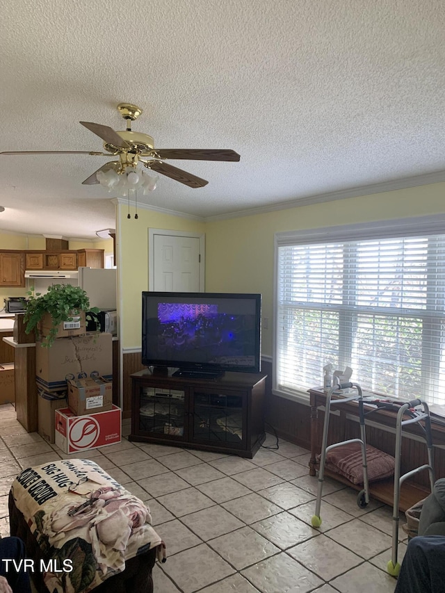 living area featuring a ceiling fan, a textured ceiling, light tile patterned flooring, and crown molding