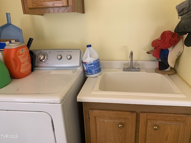 clothes washing area featuring cabinet space, washer / dryer, and a sink