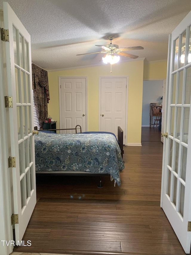 bedroom featuring french doors, a textured ceiling, multiple closets, and wood finished floors