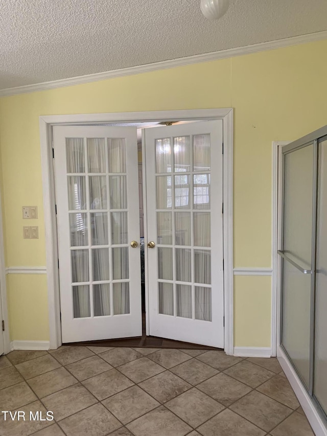 entryway with tile patterned floors, french doors, a textured ceiling, and crown molding