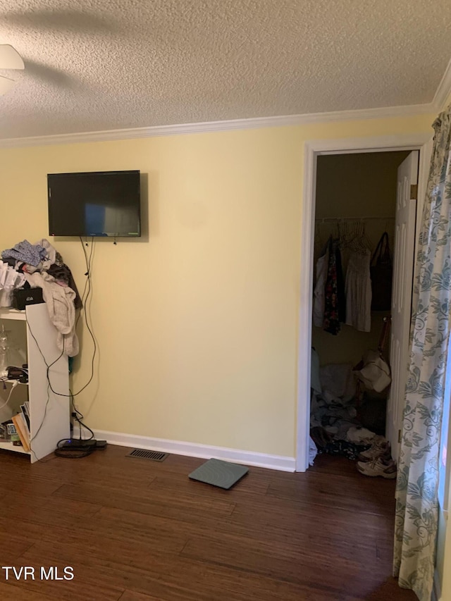 interior space featuring visible vents, a textured ceiling, wood finished floors, and crown molding