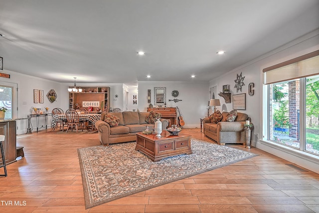 living room with recessed lighting, a chandelier, ornamental molding, and light wood finished floors