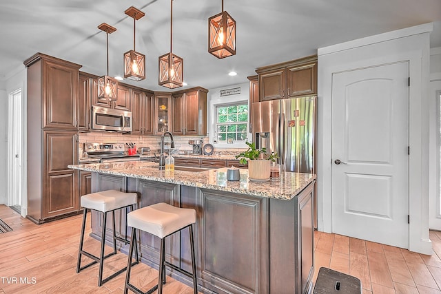 kitchen featuring tasteful backsplash, light wood-style flooring, stainless steel appliances, and a sink