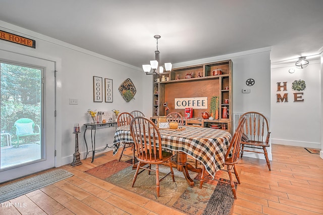 dining space featuring baseboards, a notable chandelier, crown molding, and light wood finished floors