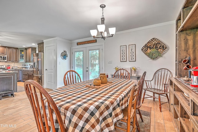 dining space with a chandelier, french doors, light wood-type flooring, and ornamental molding