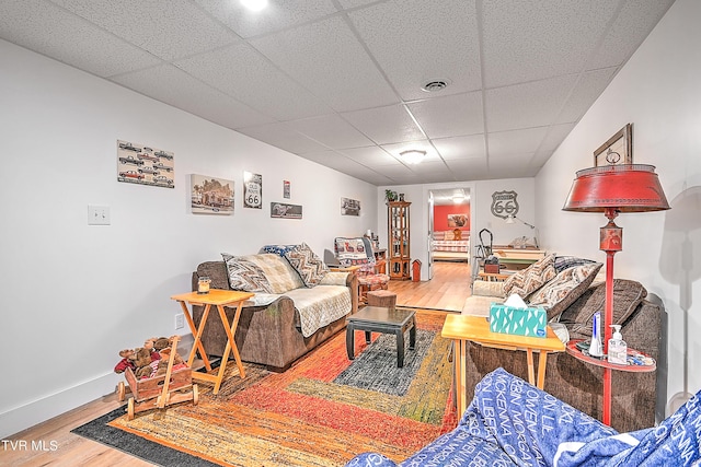 living area featuring baseboards, wood finished floors, visible vents, and a paneled ceiling