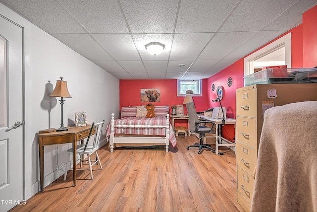 bedroom with a paneled ceiling and wood finished floors