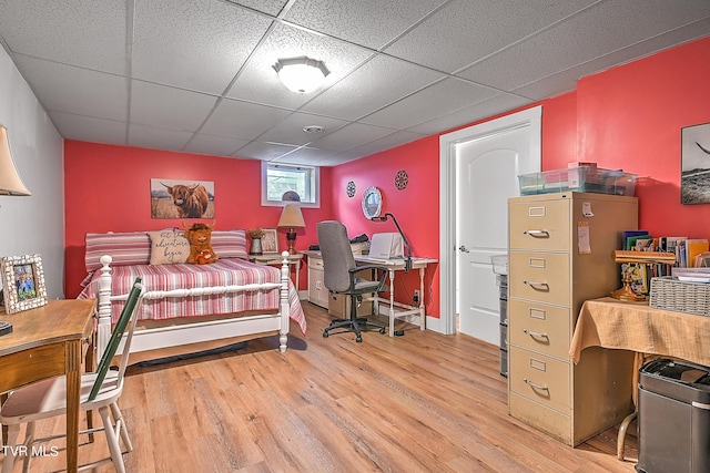 bedroom with a drop ceiling, baseboards, and wood finished floors