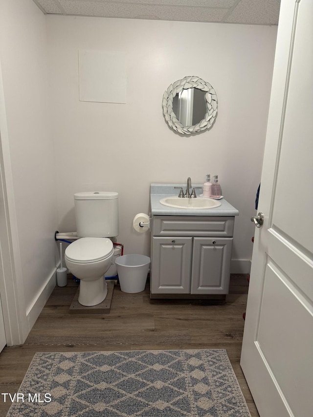 bathroom featuring vanity, toilet, wood finished floors, and baseboards