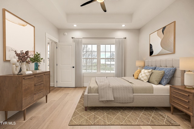 bedroom with recessed lighting, light wood-style flooring, and a raised ceiling