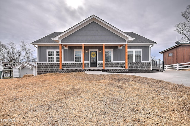 view of front of property with brick siding, board and batten siding, a shingled roof, fence, and a porch