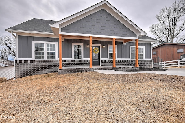 view of front of home with covered porch, board and batten siding, and roof with shingles