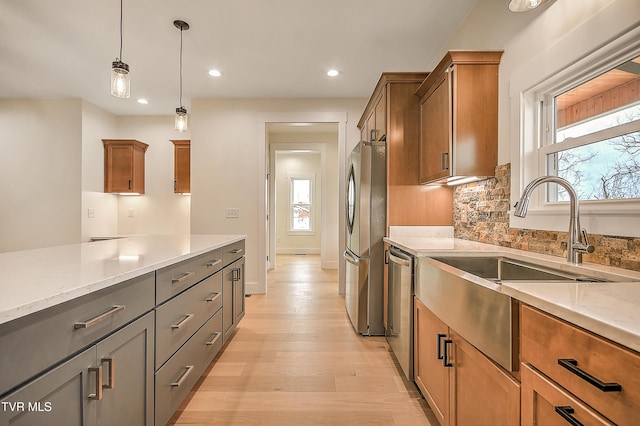 kitchen with light wood-type flooring, decorative backsplash, brown cabinets, stainless steel appliances, and a sink