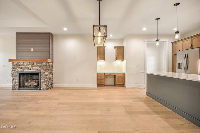 kitchen featuring light wood-style flooring, recessed lighting, stainless steel fridge with ice dispenser, a stone fireplace, and pendant lighting