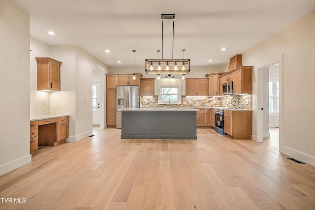 kitchen featuring a sink, decorative backsplash, built in desk, appliances with stainless steel finishes, and light wood-type flooring