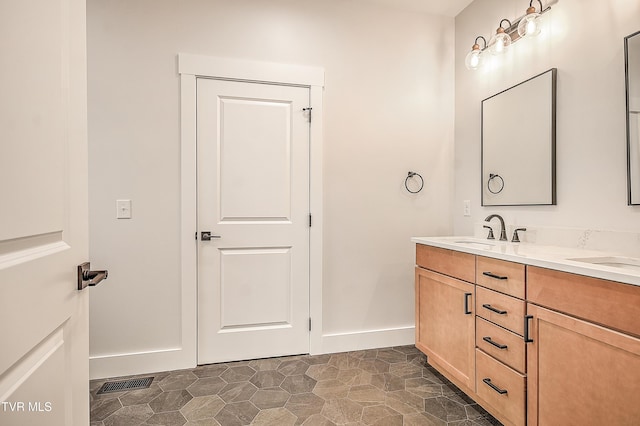 bathroom featuring a sink, visible vents, baseboards, and double vanity