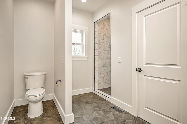 full bath with a tile shower, visible vents, toilet, and baseboards