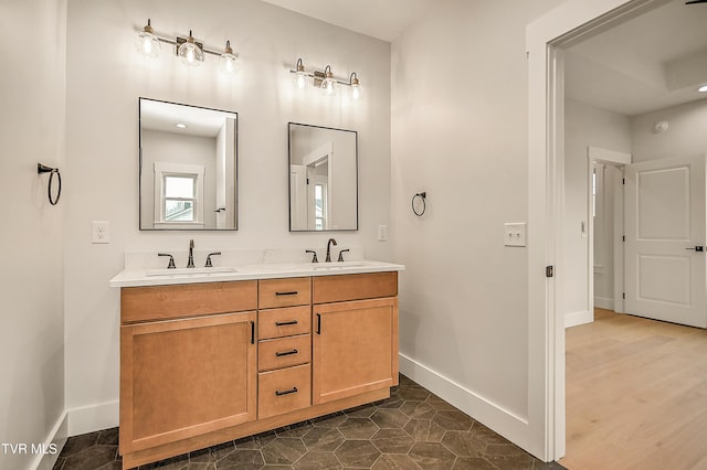 bathroom featuring double vanity, baseboards, and a sink