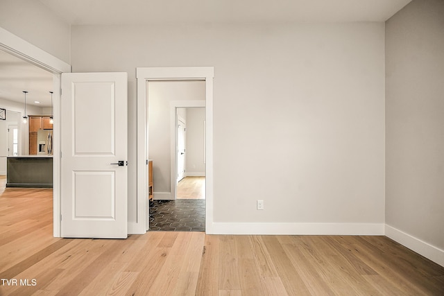 spare room featuring baseboards and light wood-style flooring