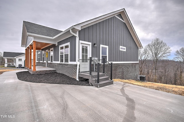 view of front of house featuring cooling unit, board and batten siding, and covered porch