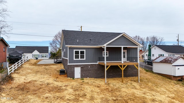 back of property featuring an outbuilding, roof with shingles, and fence