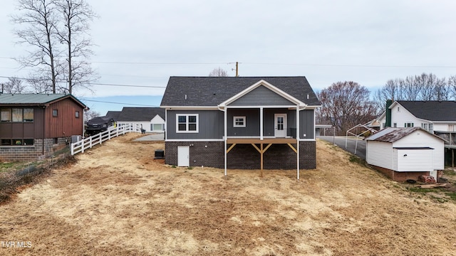 back of house with an outdoor structure, fence, and a shingled roof