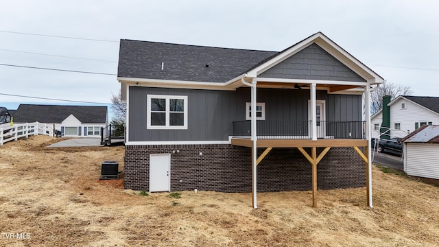 rear view of property featuring board and batten siding, central AC unit, a ceiling fan, and brick siding