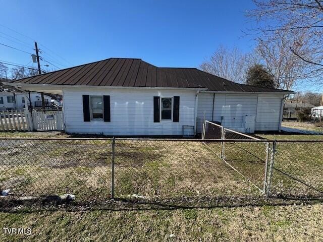 rear view of house featuring fence and metal roof