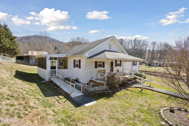 view of front of home featuring a mountain view, fence, a front yard, and a sunroom