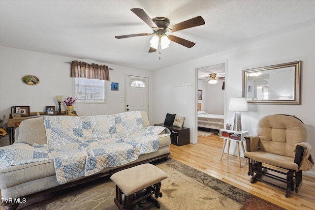 living area featuring light wood-style floors, ceiling fan, and stairs