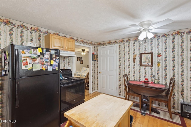 kitchen featuring wallpapered walls, black appliances, under cabinet range hood, and a textured ceiling