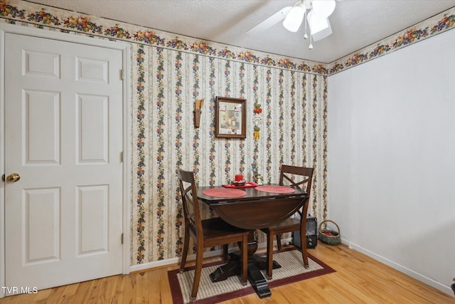 dining area with baseboards, a textured ceiling, wood finished floors, and a ceiling fan