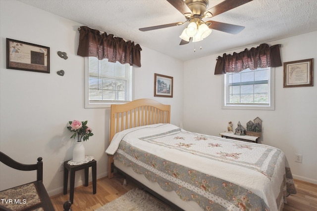 bedroom featuring ceiling fan, wood finished floors, baseboards, and a textured ceiling