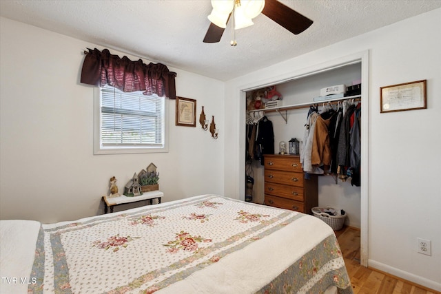 bedroom featuring ceiling fan, baseboards, light wood-type flooring, a closet, and a textured ceiling