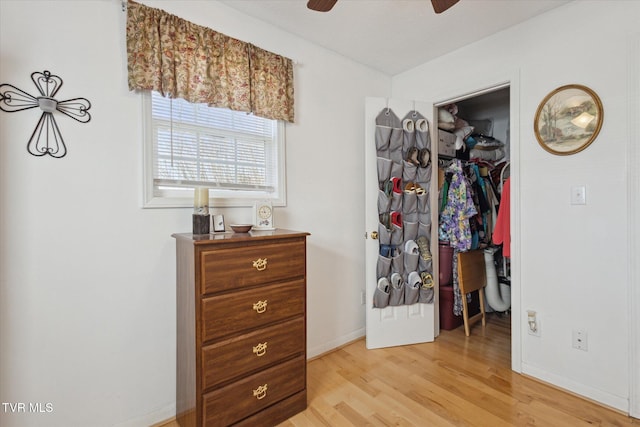 bedroom featuring a ceiling fan, baseboards, a spacious closet, light wood-style floors, and a closet