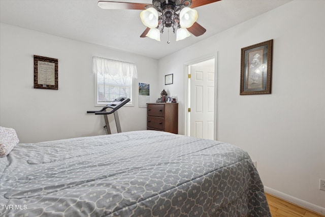 bedroom with ceiling fan, baseboards, and wood finished floors