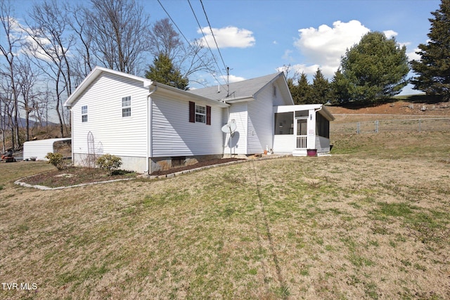 view of side of home with a yard, fence, and a sunroom