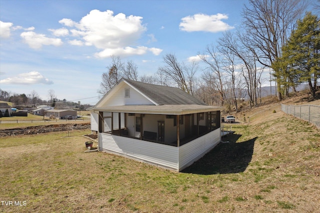 view of home's exterior with a lawn, fence, and a sunroom