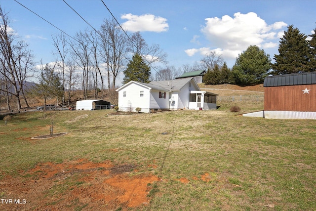 view of yard featuring an outbuilding, a storage unit, and a sunroom