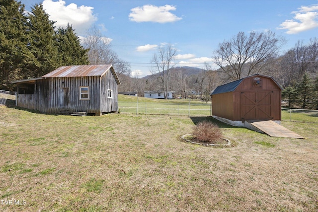 view of yard with an outbuilding, fence, a storage unit, a detached garage, and a mountain view